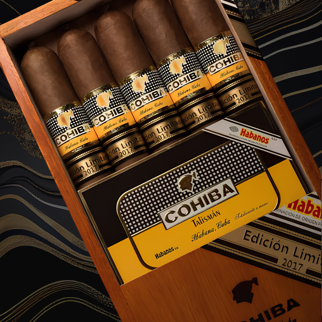 An open wooden Cohiba Talisman Limited Edition 2017 cigar box displaying several cigars with black and yellow bands, set against a dark patterned fabric background.