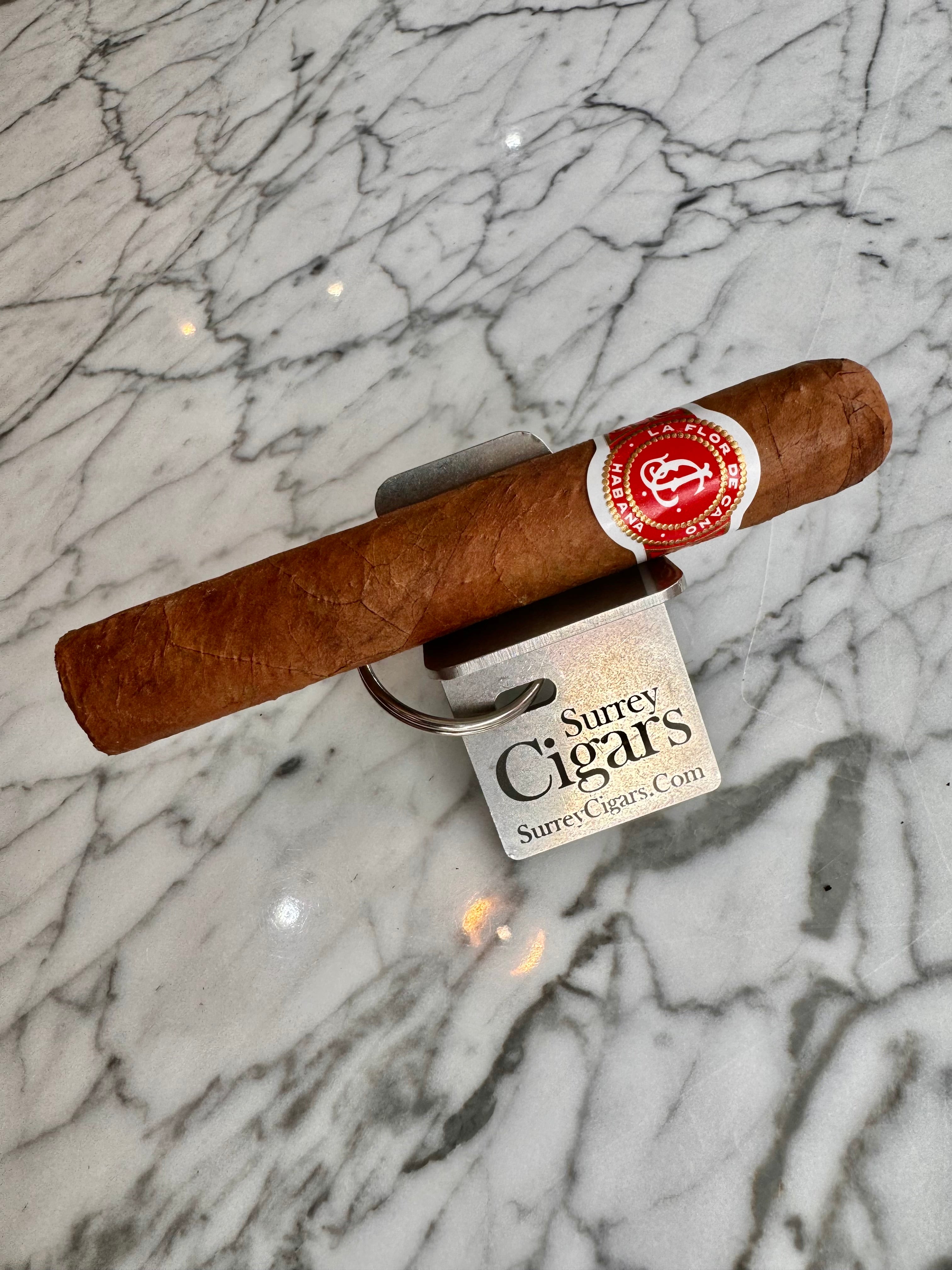 La Flor de Cano Elegidos cigar resting on Surrey Cigars branded stand on marble
