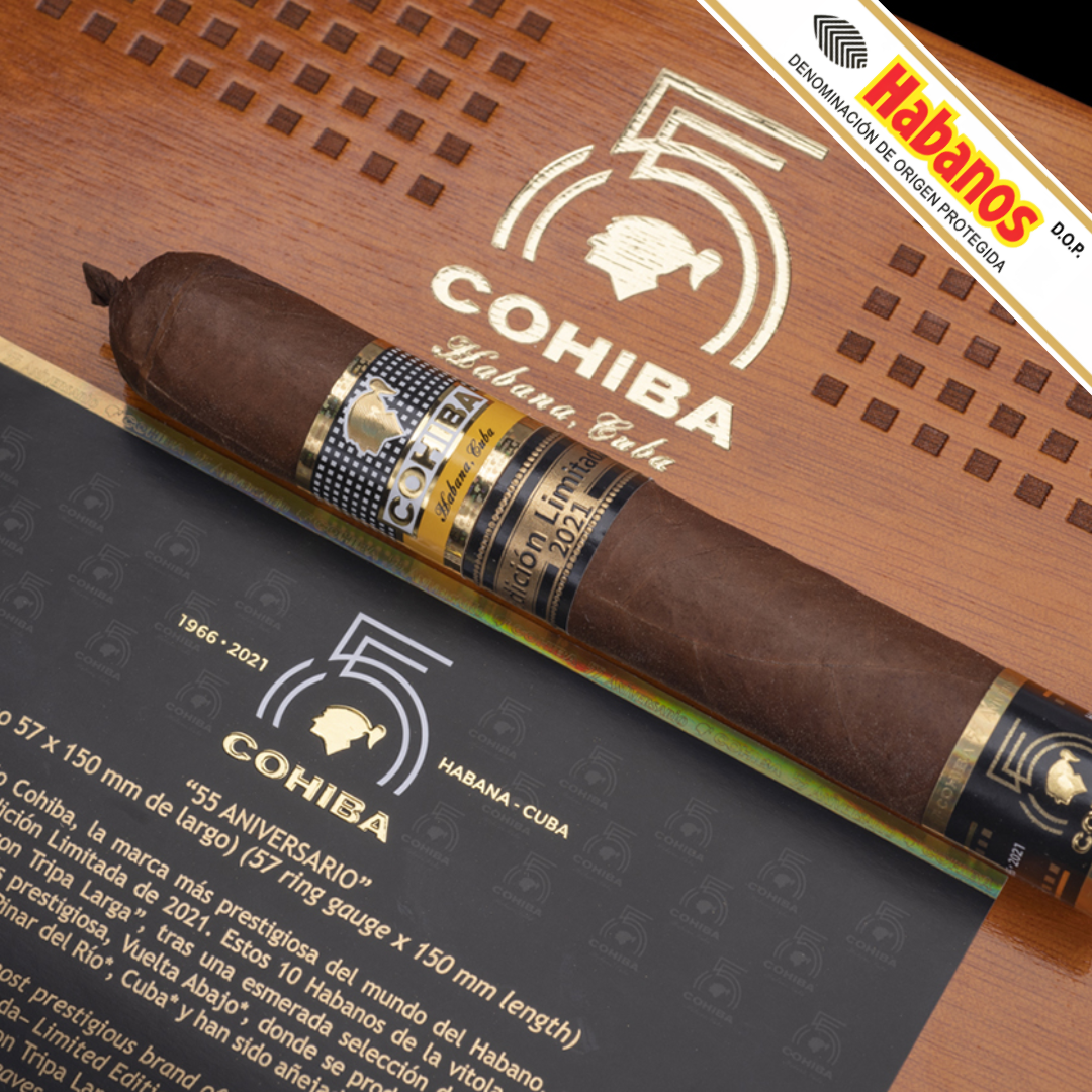A single Cohiba 55 Aniversario Limited Edition 2021 cigar placed diagonally across branded packaging, including a wooden box lid with the Cohiba logo and a dark card with anniversary text. A Habanos banner appears in the top-right corner.