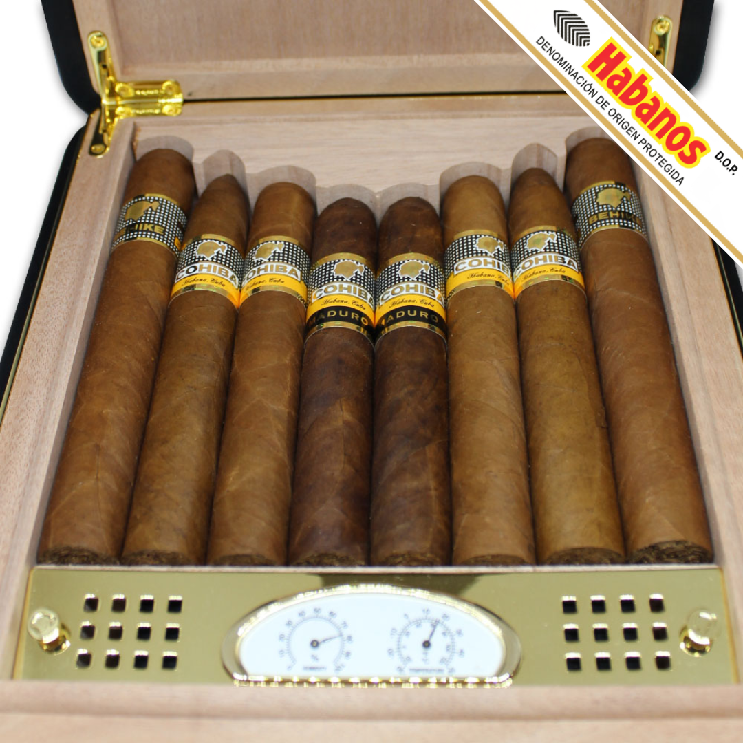 An open Cohiba Selección 50th Anniversary Travel Humidor displays 8 cigars in varying shades of brown, with gold-tone hardware and a humidity gauge. A diagonal 'Habanos' brand banner is visible in the top right corner.