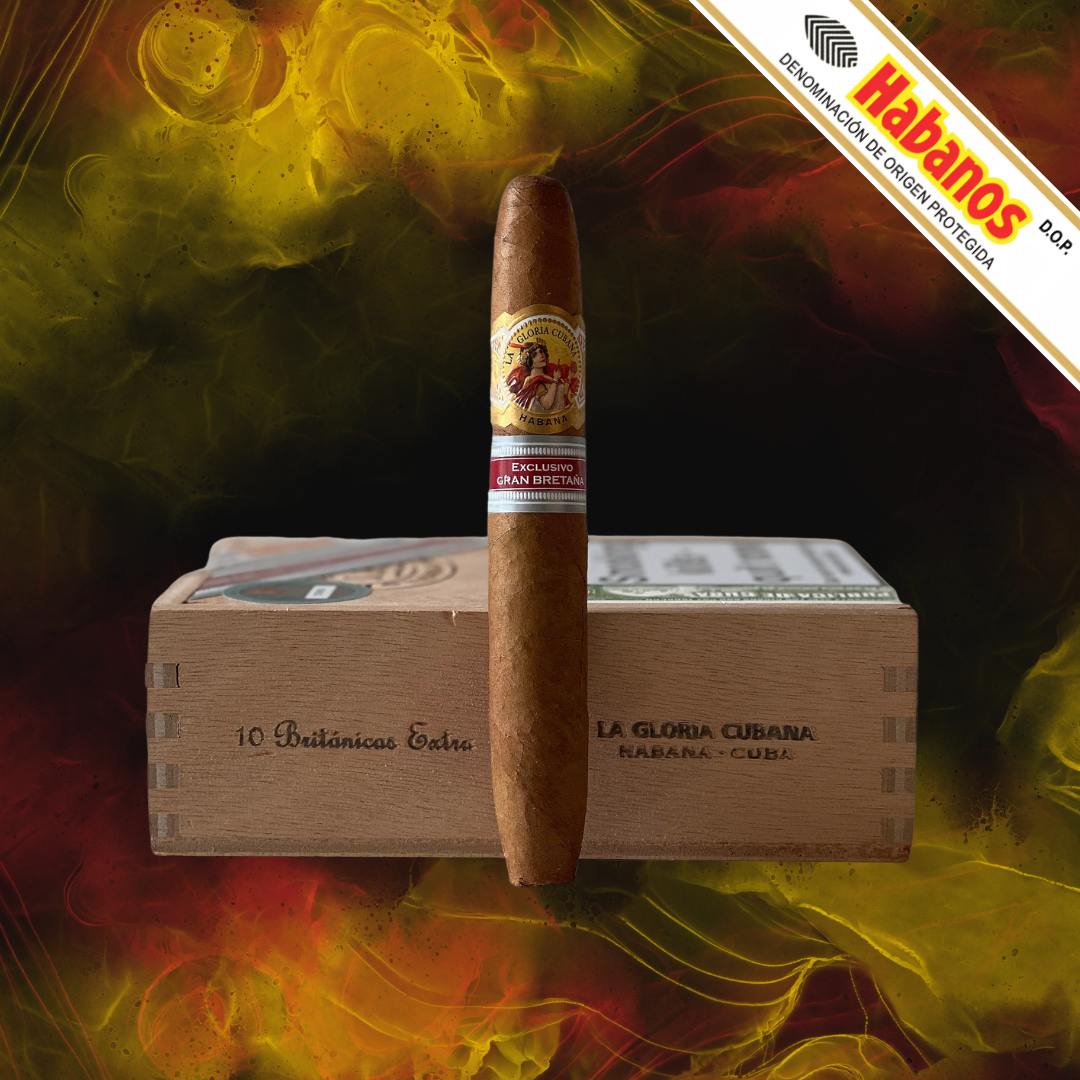 A single La Gloria Cubana Britanicas Extra UK Regional Edition 2017 cigar stands upright in front of a wooden cigar box labelled La Gloria Cubana. The background is a dramatic, dark backdrop with glowing yellow and orange smoke effects, and a diagonal banner in the top right reads Habanos.
